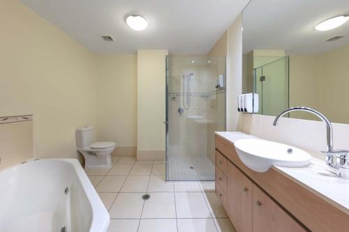 a bathroom with a shower and a sink and a toilet at Piermonde Apartments Cairns in Cairns