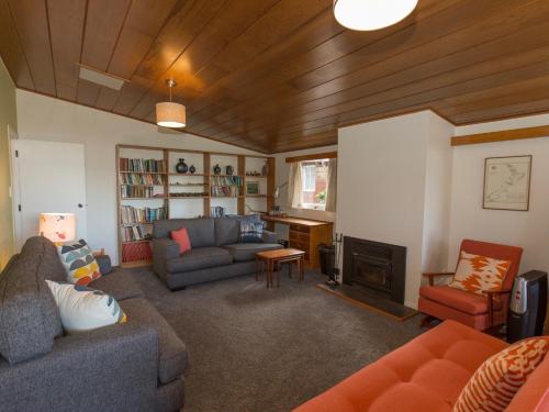a living room with a couch and a fireplace at Sixties Cedar Bach - Kuratau Holiday Home in Kuratau