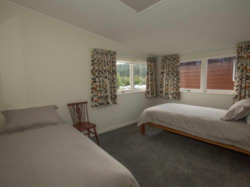 a bedroom with two beds and two windows at Sixties Cedar Bach - Kuratau Holiday Home in Kuratau
