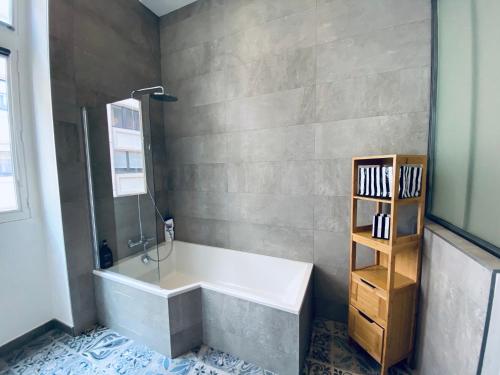 a bathroom with a bath tub and a book shelf at Hyper centre : Appartement Déco Atelier ou Studio Mezzanine in Lyon