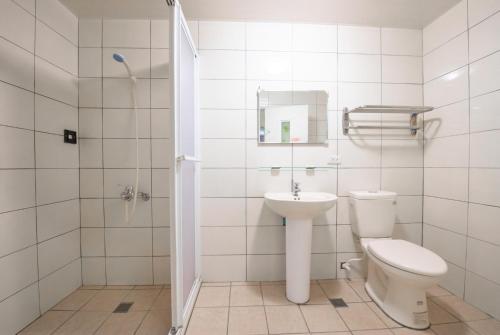 a white bathroom with a toilet and a sink at Luodong Nightmarket Homestay in Shih-pa-lieh