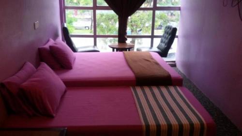 een slaapkamer met 2 bedden en een groot raam bij Hijrah Hotel in Alor Setar
