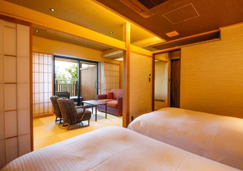 a hotel room with two beds and a table and chairs at Awaji Hamarikyu Takumi in Minamiawaji