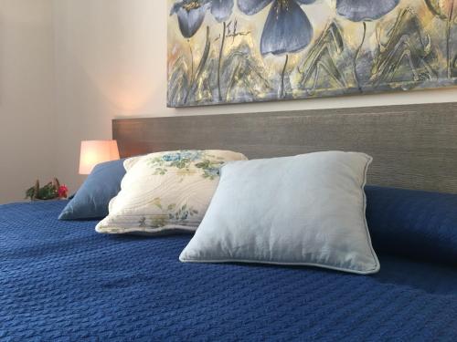 twee kussens op een blauw bed met een schilderij aan de muur bij Appartamenti del Corso in Cuneo