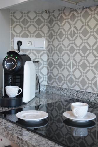 a coffee maker and two cups on a counter at Casa da Avenida in Póvoa de Varzim