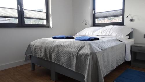 a bedroom with a bed with two blue towels on it at DOMINO-APARTAMENTY Blue in Krościenko