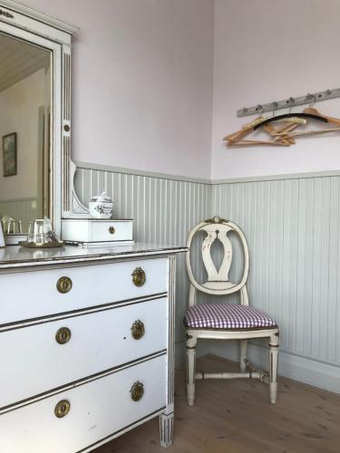 ein Badezimmer mit einer Kommode mit einem Spiegel und einem Stuhl in der Unterkunft Mellby 11 Bed & Breakfast in Kivik