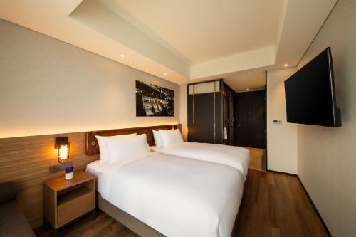 a hotel room with a bed and a flat screen tv at Mercure Ambassador Seoul Hongdae in Seoul