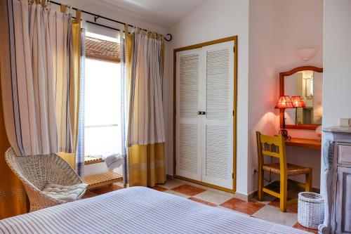 a bedroom with a bed and a desk and a window at Casa Vale Del Rei in Tavira