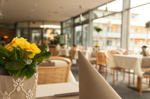 a vase with yellow flowers on a table in a restaurant at Müritz-Strandhotel in Röbel