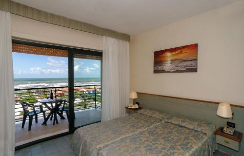 a bedroom with a bed and a balcony with the ocean at Hotel Paris in Lido di Camaiore