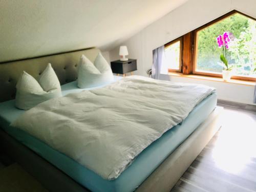a bedroom with a large white bed with a window at Ferienhäuschen im Grünen in Weimar