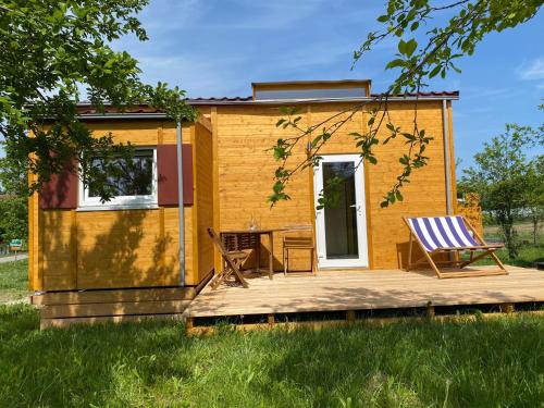 una casa pequeña con terraza y 2 sillas en Biolandhof Bodensee, en Markdorf