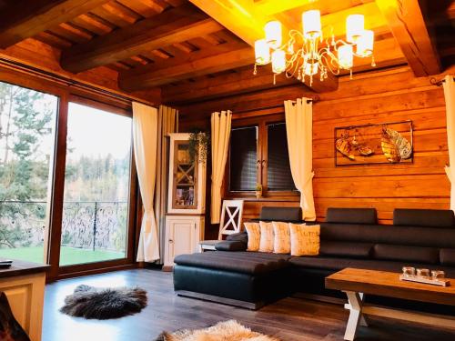 a living room with a black couch and a chandelier at ZRUB BINDT in Hnilčík