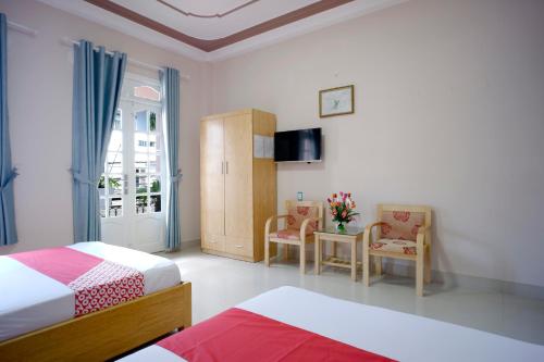 een slaapkamer met 2 bedden en 2 stoelen en een televisie bij OYO 987 Thanh Thanh Nhan Hotel in Da Lat