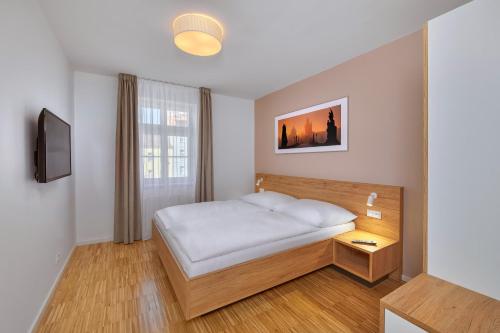 a small bedroom with a bed and a window at Downtown Suites Kodanska in Prague