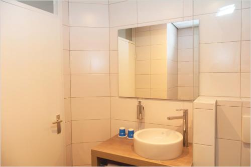 La salle de bains blanche est pourvue d'un lavabo et d'un miroir. dans l'établissement Fletcher Hotel Restaurant De Gelderse Poort, à Ooij