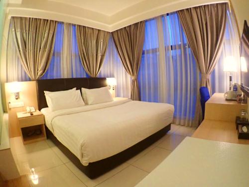 a bedroom with a large bed with blue curtains at De Elements Business Hotel KL in Kuala Lumpur