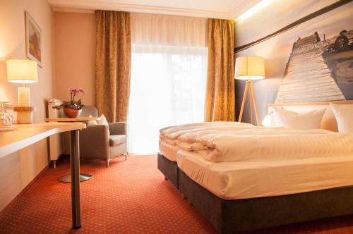 レーベルにあるMüritz-Strandhotelのベッド、デスク、窓が備わるホテルルームです。