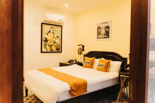 a bedroom with a bed with orange and white pillows at Hue 1962 INN in Hue