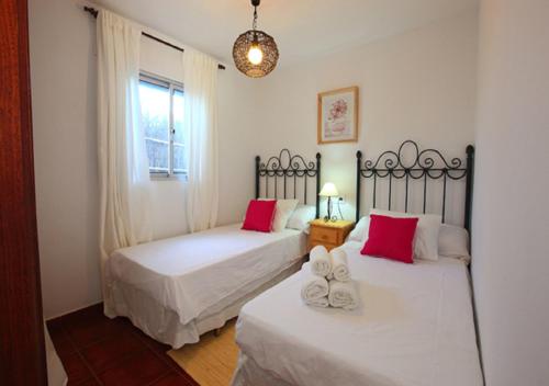 2 Betten in einem Zimmer mit roten und weißen Kissen in der Unterkunft LA CASA DE LA PLAYA 1 in Tarifa