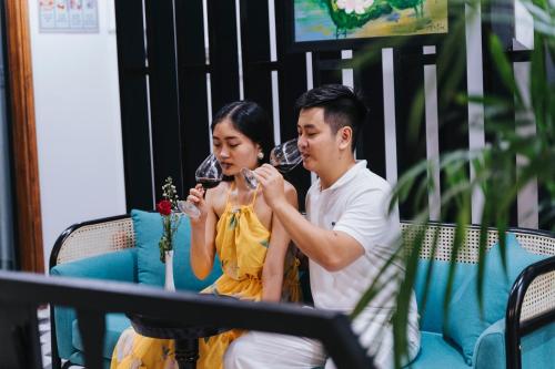 a man and woman sitting on a couch drinking wine at Hue 1962 INN in Hue