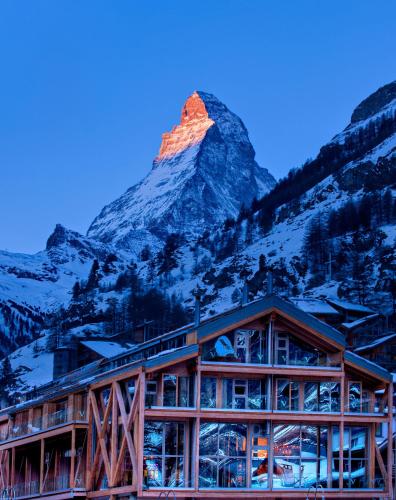 a building with a mountain in the background at Backstage Boutique SPA Hotel in Zermatt
