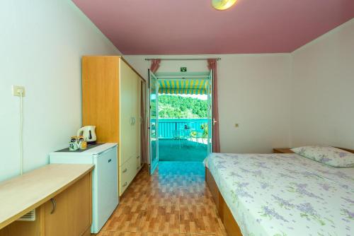 - une chambre avec un lit et une porte donnant sur un balcon dans l'établissement Guest House Radulj, à Polače