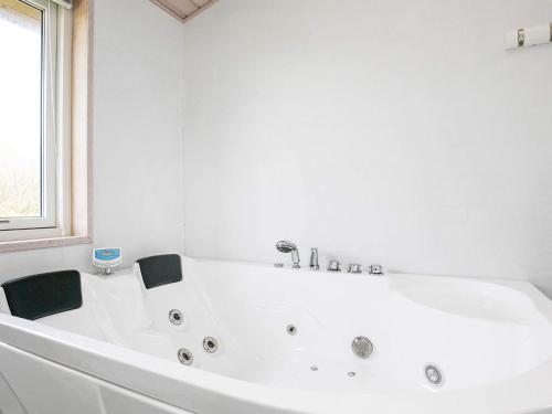 baño blanco con bañera blanca y ventana en 6 person holiday home in L kken, en Løkken