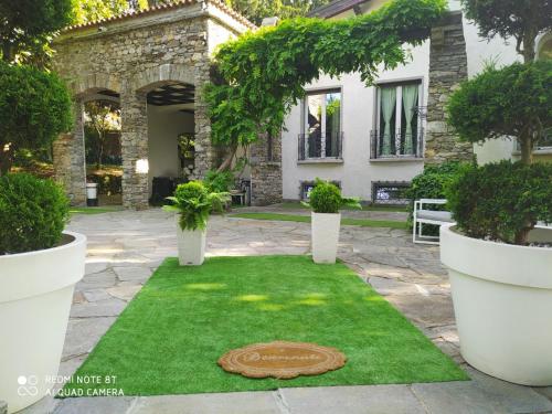 "La Selvetta" bed and breakfast في Buguggiate: حديقة بها رقعة دائرية من العشب أمام المنزل