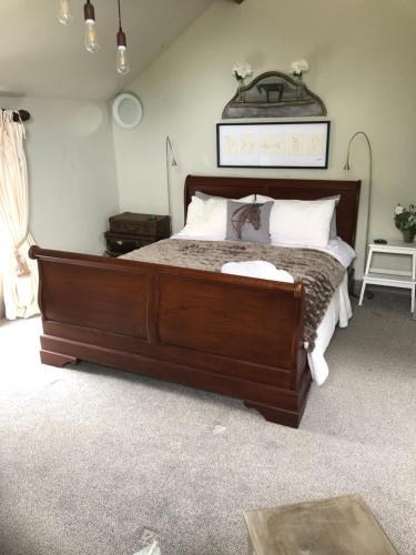 a bedroom with a large wooden bed with white pillows at The Jockey Room Hideaway in Spurstow