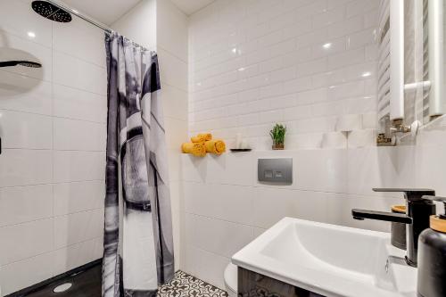baño blanco con ducha y lavamanos en Kościelna Loft Apartaments, en Rybnik