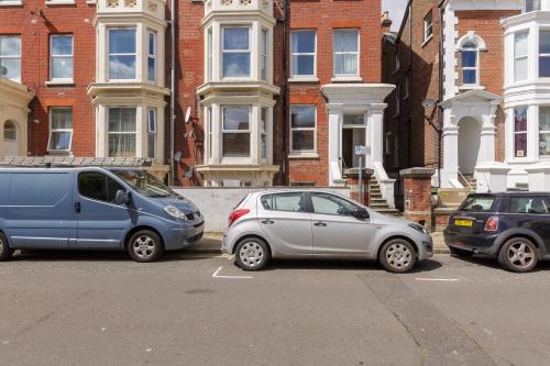 three cars parked in a parking lot in front of a building at Stopover at SEABIRD APARTMENTS central Southsea in Portsmouth