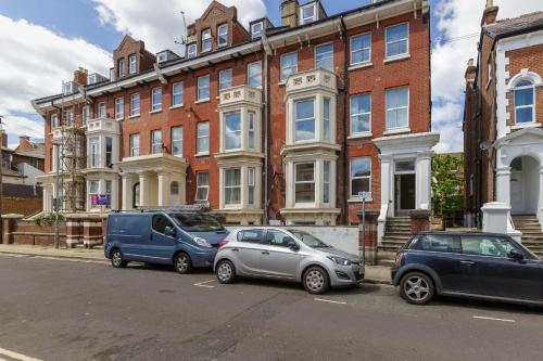 three cars parked in front of a large brick building at Stopover at SEABIRD APARTMENTS central Southsea in Portsmouth