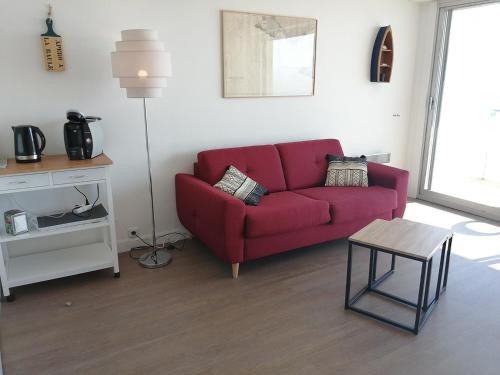 a living room with a red couch and a table at Cap sur l'Océan pour 3 personnes in La Baule