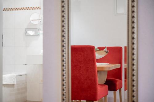 a mirror with a table and a red chair in a bathroom at Bühlhof Appartements in Lech am Arlberg