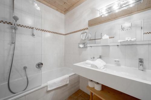 a white bathroom with a shower and a sink at Bühlhof Appartements in Lech am Arlberg