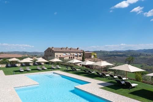 a villa with a swimming pool and umbrellas at Hotel Le Fontanelle in Castelnuovo Berardenga