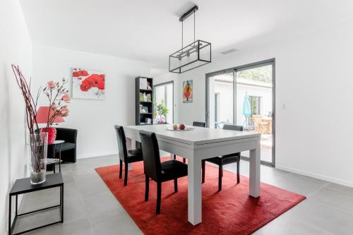 a dining room with a white table and black chairs at Villa Géna in Saint-Médard-dʼEyrans