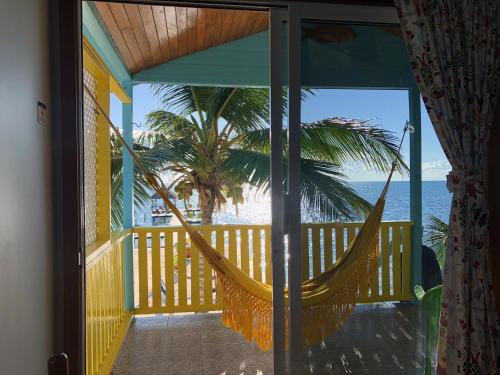 a hammock on a balcony with a view of the beach at Colinda Cabanas in Caye Caulker
