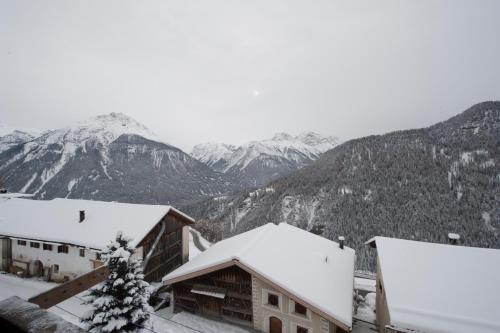 a snowy mountain range with snow covered buildings and mountains at Chasa Rosa in Vna