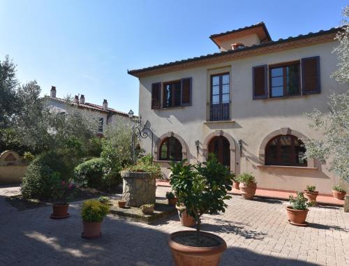 une grande maison avec des plantes en pot dans une cour dans l'établissement CASE&COLLINE Villa Laura, à Montescudaio