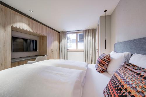 a bedroom with a large white bed and a tv at Bühlhof Appartements in Lech am Arlberg