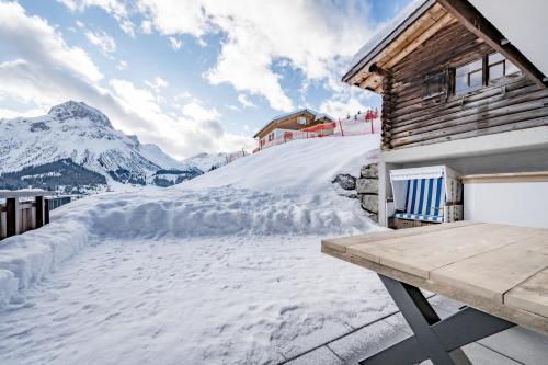a snow covered road next to a wooden house at Bühlhof Appartements in Lech am Arlberg