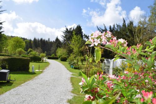 um caminho de cascalho num jardim com flores cor-de-rosa em La Pointe Camping em Châteaulin
