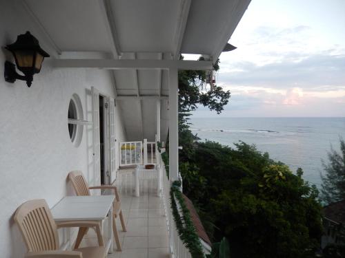 a balcony with a table and chairs and the ocean at Moon San Villa at the Blue Lagoon in Port Antonio