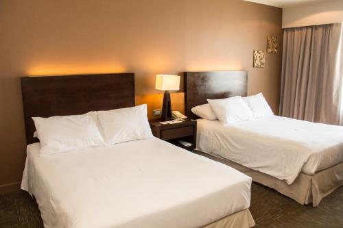 two beds in a hotel room with white sheets at LRH Calama, an Ascend Collection Hotel in Calama