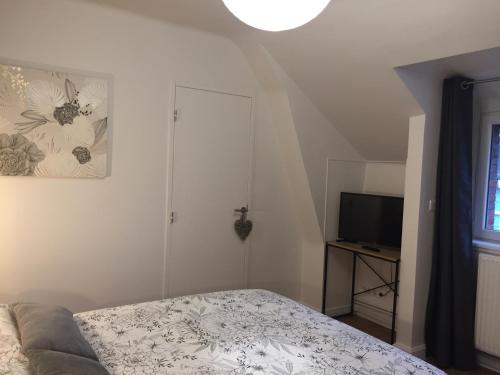a small bedroom with a bed and a television at L'ESCALE FONTAINE SIMON in Fontaine-Simon