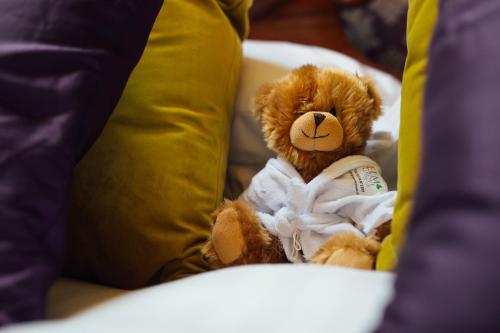 a teddy bear sitting on a couch with pillows at Elm Grove Country House in Tenby