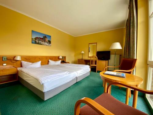 una habitación de hotel con una cama grande y una mesa en Park Hotel Fasanerie Neustrelitz, en Neustrelitz